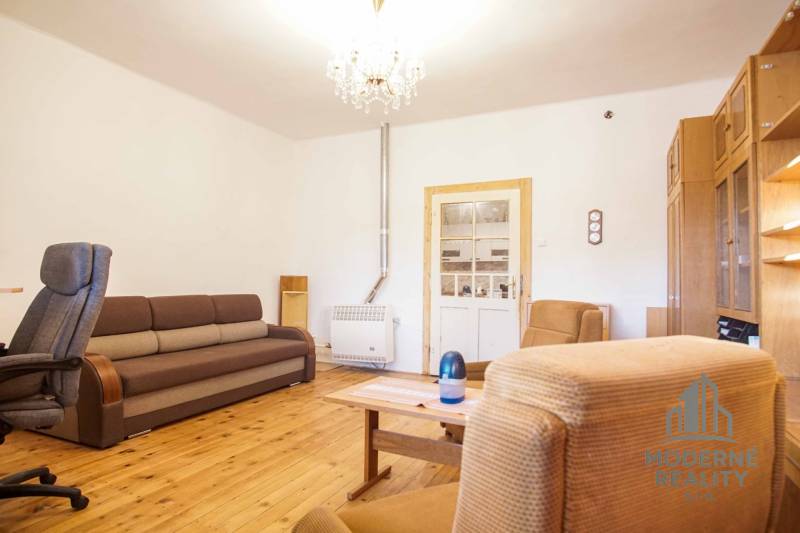 Obývací pokoj v rodinném domě s podlahou s dřevěným dekorem, pohovkou a křesly.