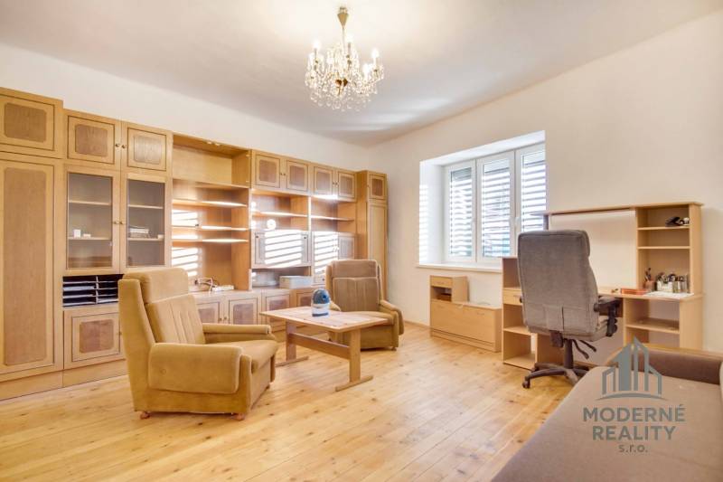 Interiér rodinného domu s nábytkem, podlahou s dřevěným dekorem a lustrem.