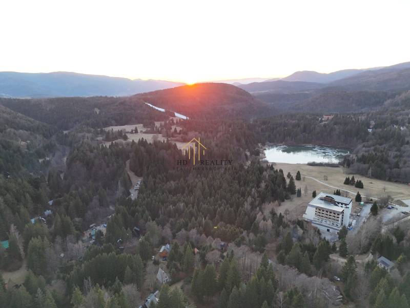 Západ slunce v Krpáčově nad lesy, jezerem a budovami na ulici Krpáčovo.