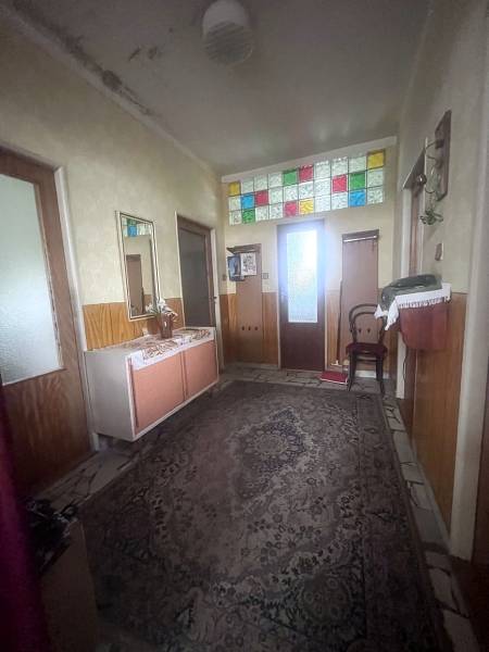 Chodba v rodinném domě má koberec a barevná skleněná okénka nad dveřmi.