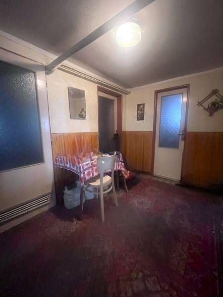 Interiér rodinného domu s dřevěným obložením, stolem a židlí.