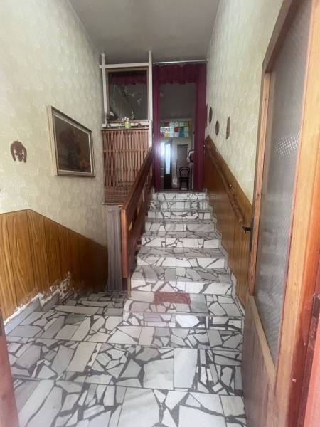 Schodiště s mozaikovou dlažbou, dřevěným zábradlím a ozdobnou tapetou v rodinném domě.