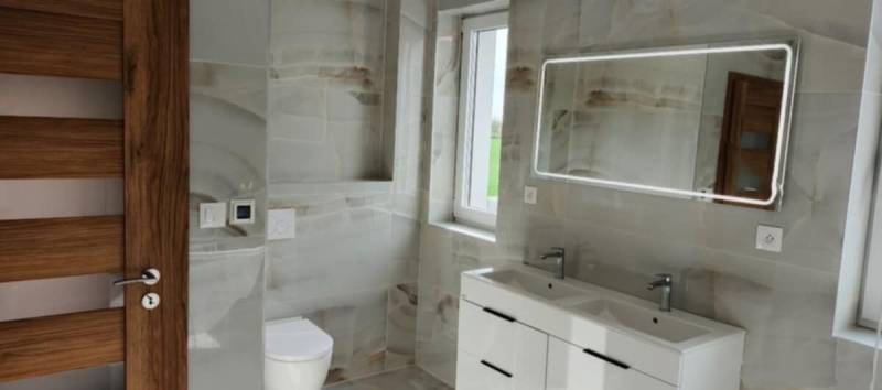 Koupelna s moderním umyvadlem, zrcadlem s osvětlením a obklady ve 3-pokojovém bytě.