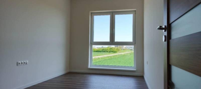 Světlá místnost v 3-pokojovém bytě s podlahou s dřevěným dekorem a velkým oknem.