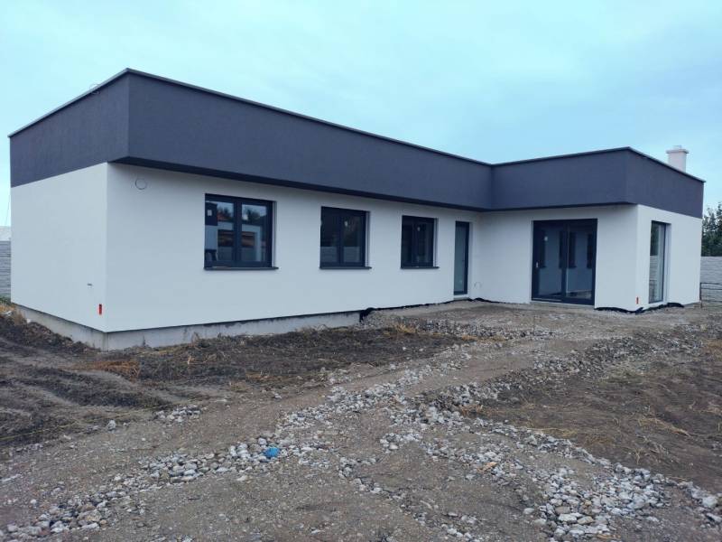 Rodinný dům v Žihárci s plochou střechou a světlou fasádou.