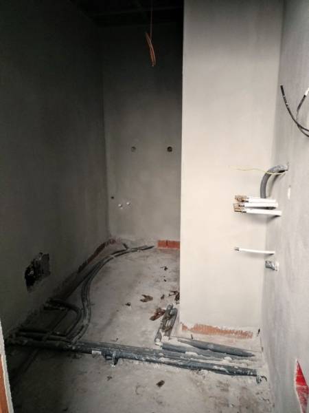 Interiér rodinného domu během renovace s viditelnými rozvody a nehotovými stěnami.