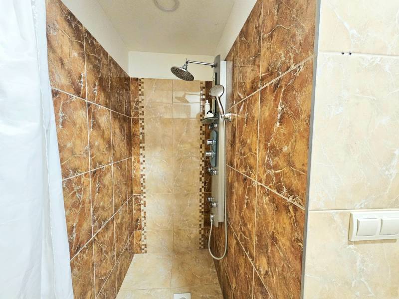 Sprchový kout s keramickým obkladem a závěsem ve 3-pokojovém bytě.