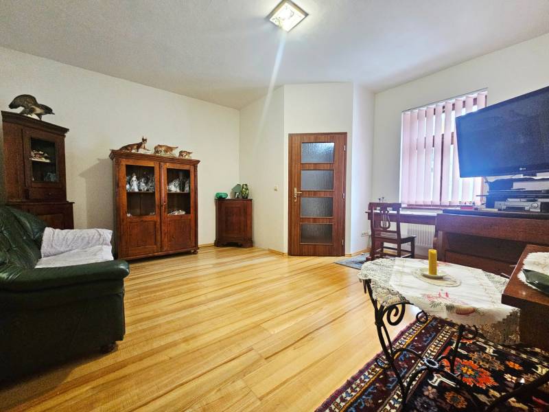 Obývací pokoj v 3-pokojovém bytě s podlahou s dřevěným dekorem a nábytkem z tmavého dřeva.