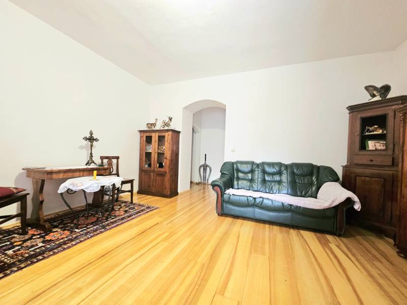 Obývací pokoj v 3pokojovém bytě s podlahou s dřevěným dekorem a dřevěným nábytkem.