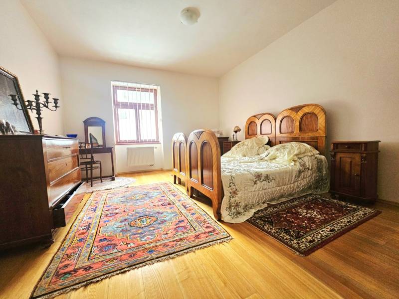 Ložnice s dřevěným nábytkem a dekorem, koberec, 3-pokojový byt, podlaha s dřevěným dekorem.