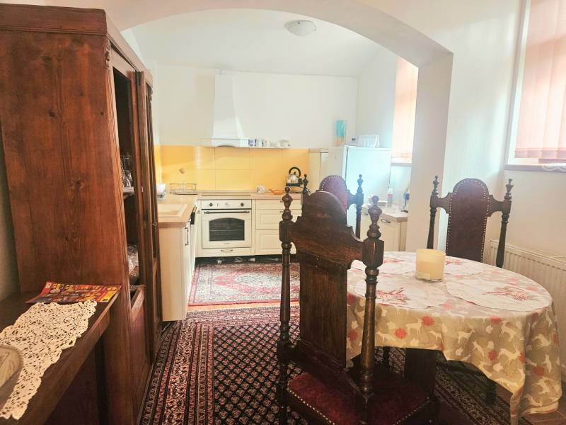 Kuchyně v 3-pokojovém bytě s dřevěným nábytkem a vintage kobercem.