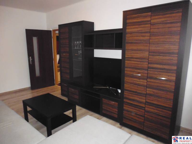 Obývací pokoj s nábytkem a podlahou s dřevěným dekorem v 2pokojovém bytě.