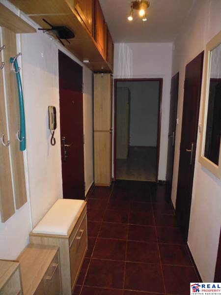 Chodba 2-pokojového bytu s tmavou dlažbou a dřevěným dekorem nábytku.