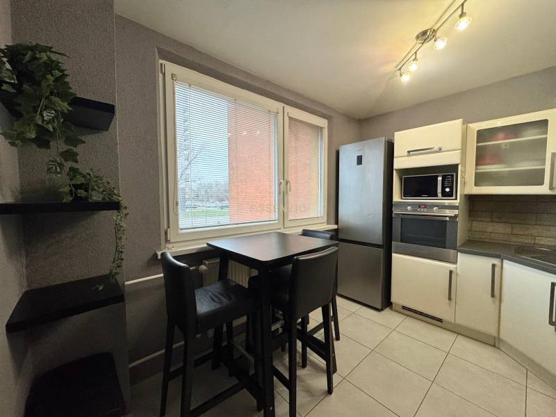 Kuchyně v 3-pokojovém bytě s moderní linkou a jídelním stolem.