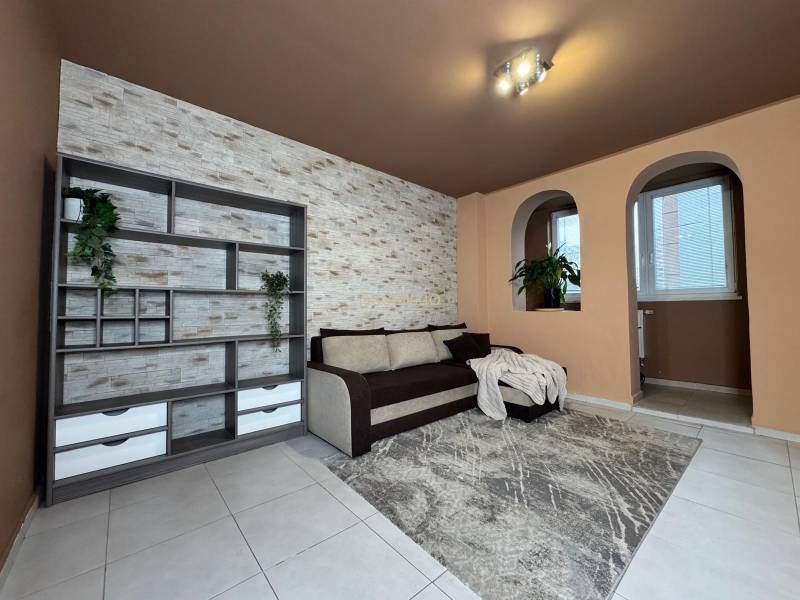 Obývací pokoj v 3-pokojovém bytě s pohovkou, policemi a dekorativní stěnou.