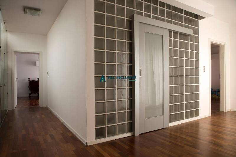 Interiér rodinného domu s prosklenými dveřmi a podlahou s dřevěným dekorem.