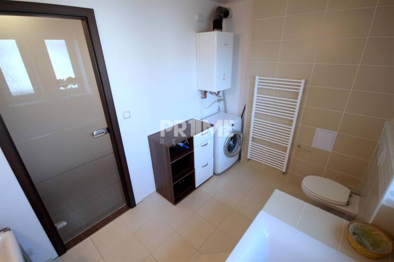 Koupelna s vanou, umyvadlem, pračkou a skříňkami v 2-pokojovém bytě.