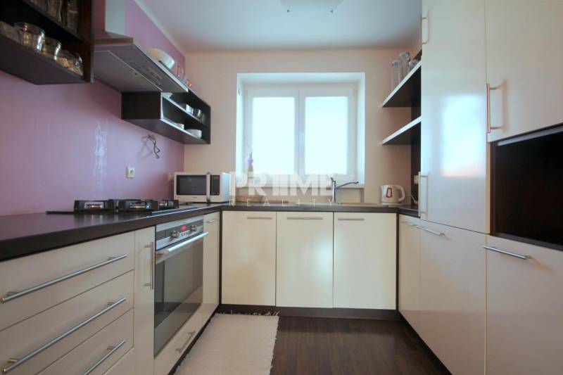 Kuchyně v 2pokojovém bytě s plynovým sporákem a podlahou s dřevěným dekorem.