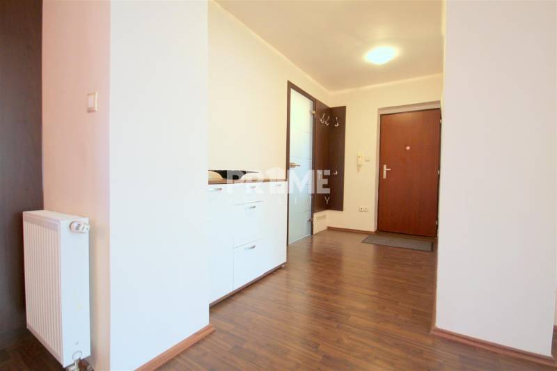 Vstupní hala v 2-pokojovém bytě s podlahou s dřevěným dekorem, bílou komodou a závěsnými háčky.