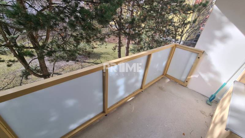 Balkon 2-pokojového bytu s výhledem na zeleň, s průhledným zábradlím.