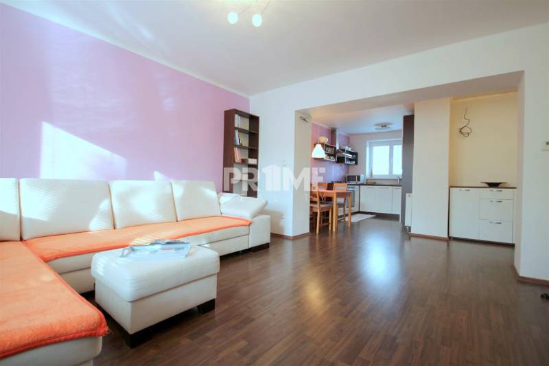 Obývací pokoj v 2-pokojovém bytě s rohovou sedačkou a podlahou s dřevěným dekorem.