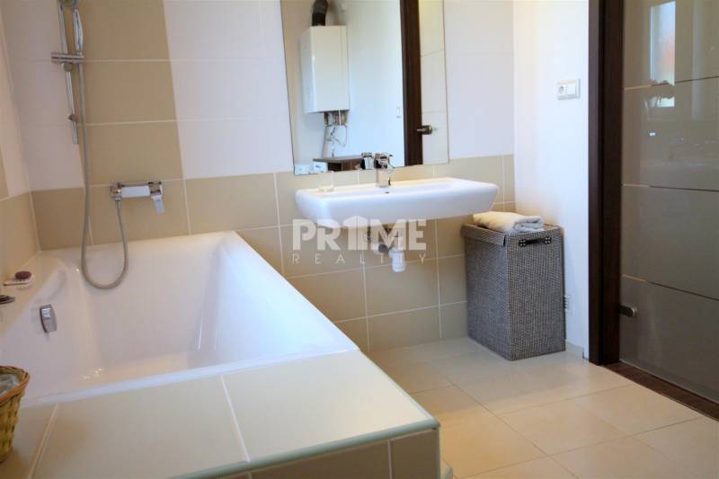 Koupelna s vanou, umyvadlem a košem na prádlo v 2-pokojovém bytě.