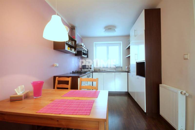 Kuchyně v 2-pokojovém bytě s podlahou s dřevěným dekorem a růžovými doplňky.