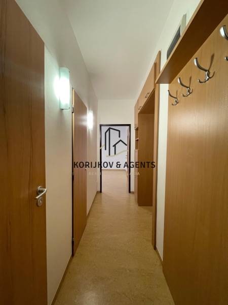 Chodba v 2-pokojovém bytě s podlahou s dřevěným dekorem a věšákem na stěně.