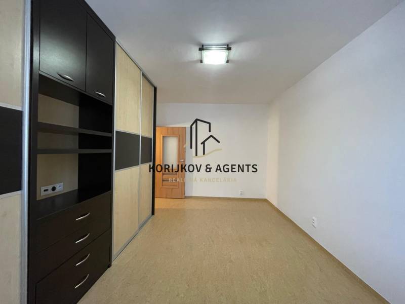 Pokoj s úložnými prostory a podlahou s dřevěným dekorem v 2-pokojovém bytě.