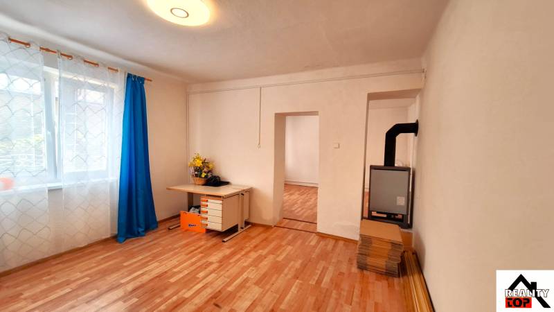 Rodinný dům s podlahou s dřevěným dekorem, okno se záclonami a psací stůl.