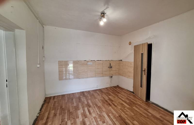 Prázdná místnost v rodinném domě s dlaždicemi a podlahou s dřevěným dekorem.