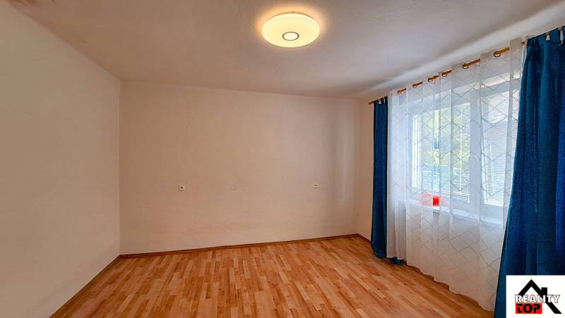 Pokoj v rodinném domě s podlahou s dřevěným dekorem a závěsy u okna.