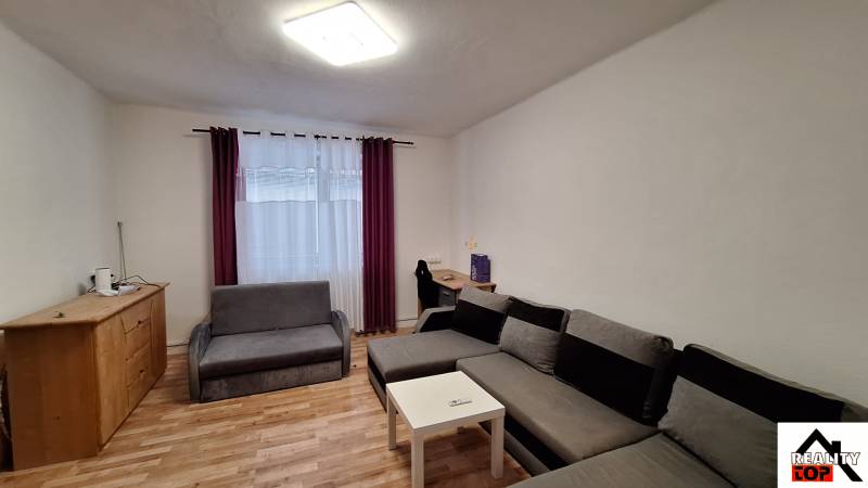 Obývací pokoj v rodinném domě s rohovou sedačkou a podlahou s dřevěným dekorem.