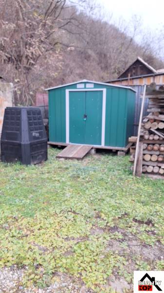 Rodinný dům v Hajnáčce se zeleným zahradním domkem, kompostérem a skladem dřeva.