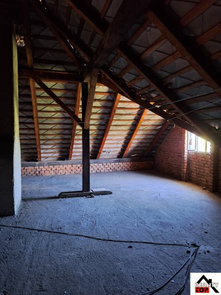 Podkroví v rodinném domě s odhalenými cihlami a podpovrchovou konstrukcí střechy.