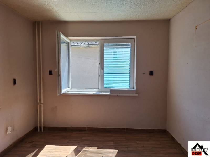 Pokoj v rodinném domě s otevřeným oknem a podlahou s dřevěným dekorem.