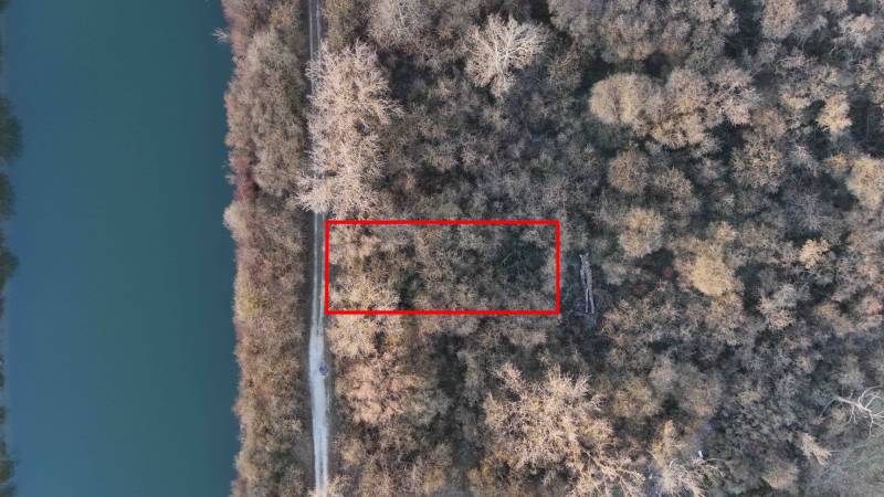 Letecký pohled na rekreační pozemky v Nové Vsi nad Váhem, obklopené lesem a řekou.