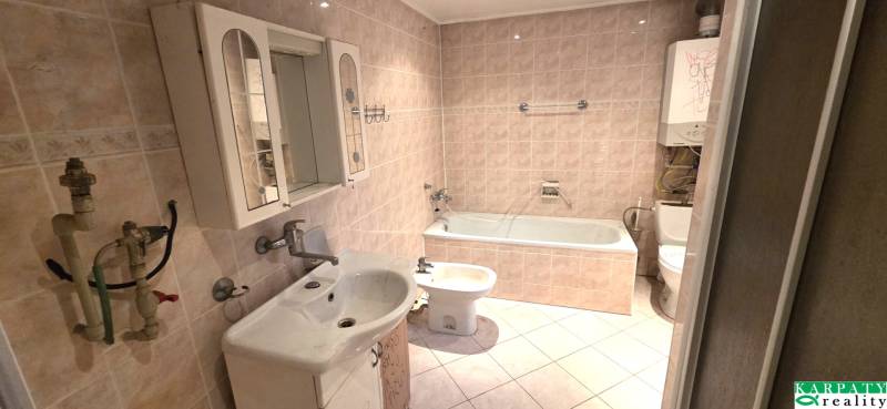 Koupelna s vanou, umyvadlem a zrcadlovou skříňkou v rodinném domě.