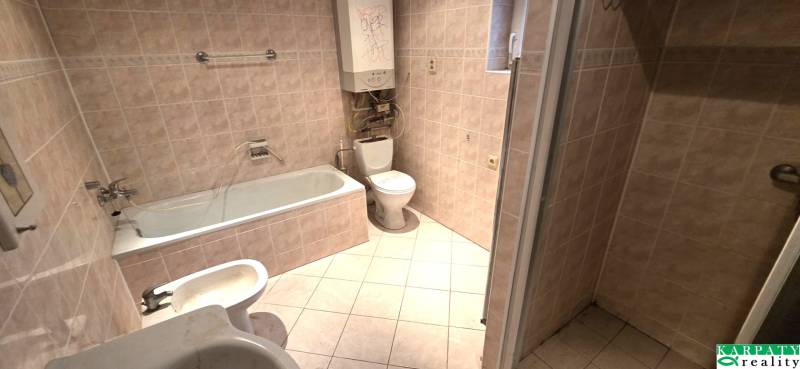 Koupelna v rodinném domě s vanou, umyvadlem a WC. Obklady světlé barvy.