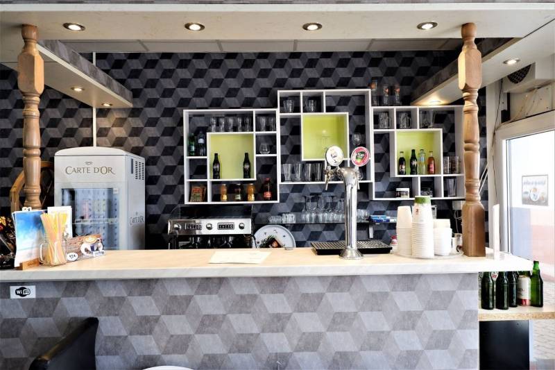 Barový pult s nápoji a pivními kohoutky v obchodních prostorách.