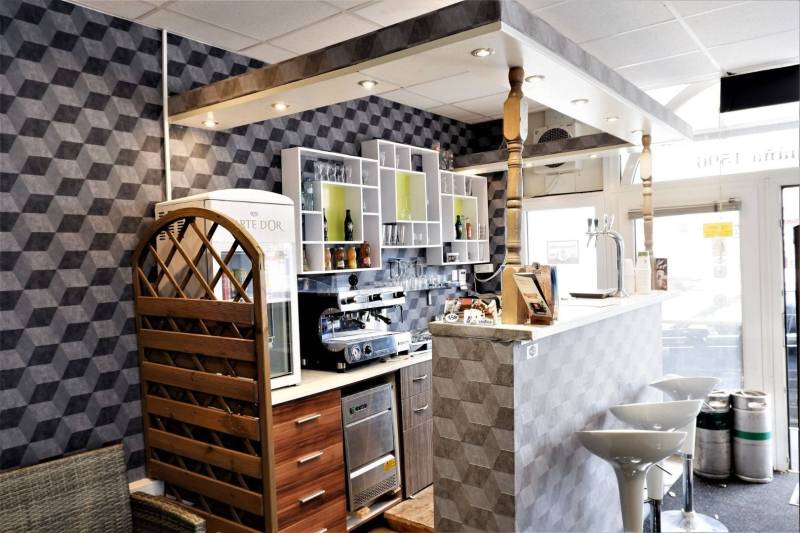 Interiér obchodních prostor s barovým pultem, dekorativními stěnami a barovými židlemi.