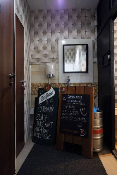 Interiérové obchodní prostory se zrcadlem, umyvadlem a tabulemi s nabídkou nápojů.