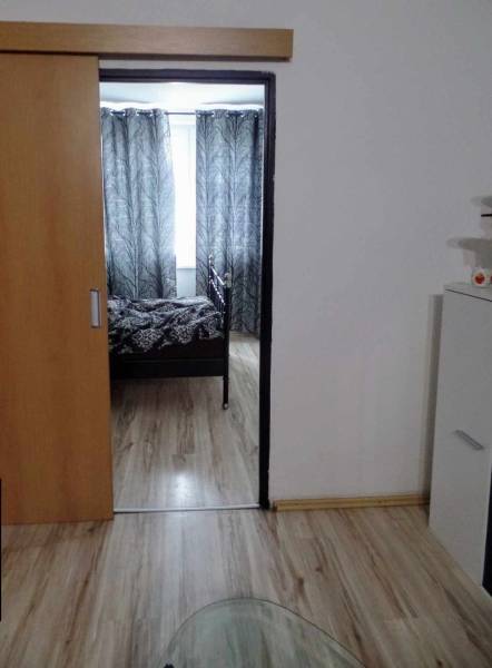 Interiér s podlahou s dřevěným dekorem, posuvnými dveřmi a černobílými závěsy v 3-pokojovém bytě.