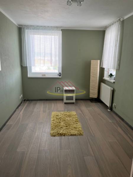 Pokoj ve 4pokojovém bytě s podlahou s dřevěným dekorem a zelenými stěnami.