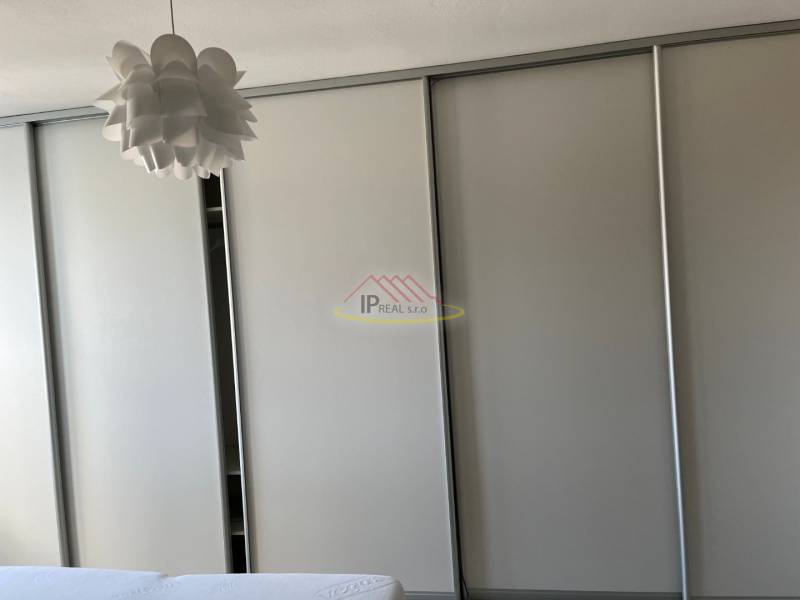 Vestavěná skříň se světlým dekorem a originální stropní lustr ve 4pokojovém bytě.