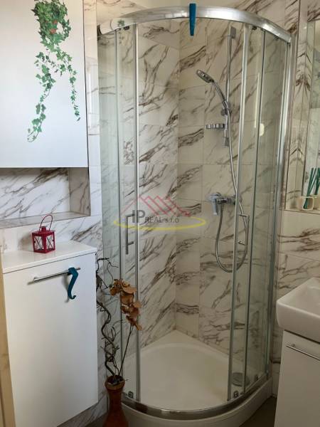 Kompaktní koupelna se sprchovým koutem a mramorovým obkladem ve 4pokojovém bytě.