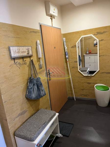 Interiér předsíně ve 4-pokojovém bytě s věšákem, lavicí a zrcadlem.