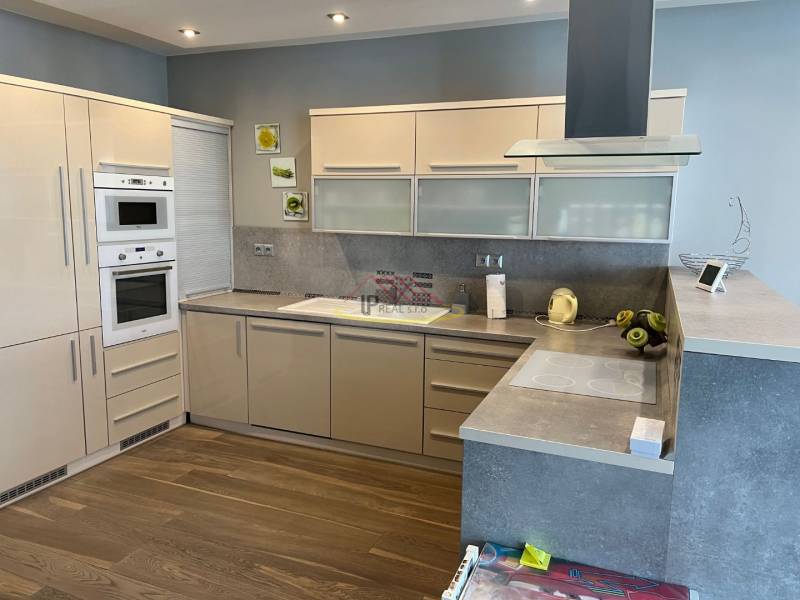 Kuchyně ve 4-pokojovém bytě, vestavěné spotřebiče, podlaha s dřevěným dekorem.