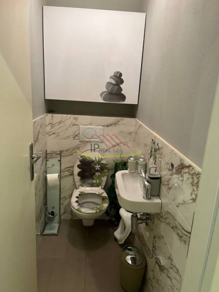 Koupelna ve 4-pokojovém bytě s mramorovými obklady a moderním umyvadlem.