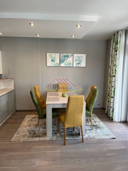 Jídelní kout ve 4-pokojovém bytě s pestrými židlemi a podlahou s dřevěným dekorem.